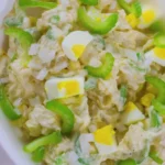 Creamy Hellmann’s potato salad recipe with eggs, celery, dill, and paprika in a white bowl.