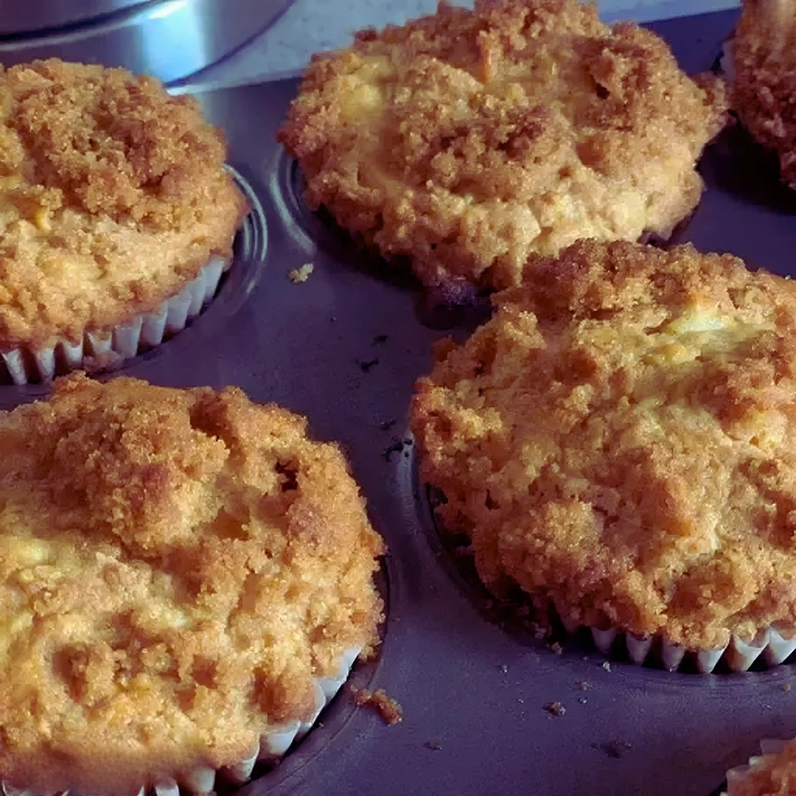 Apple Cinnamon Muffins Recipe 6 Freshly baked apple cinnamon muffins recipe with golden crumb topping cooling in muffin tin.